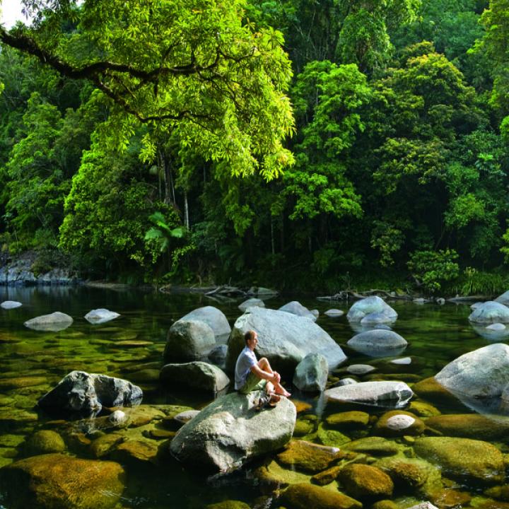 Man sitting on a rock in the middle of a river
