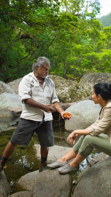 A couple receiving a tour in the jungle by a river