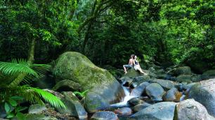 Couple sitting back to back on some rocks by the river